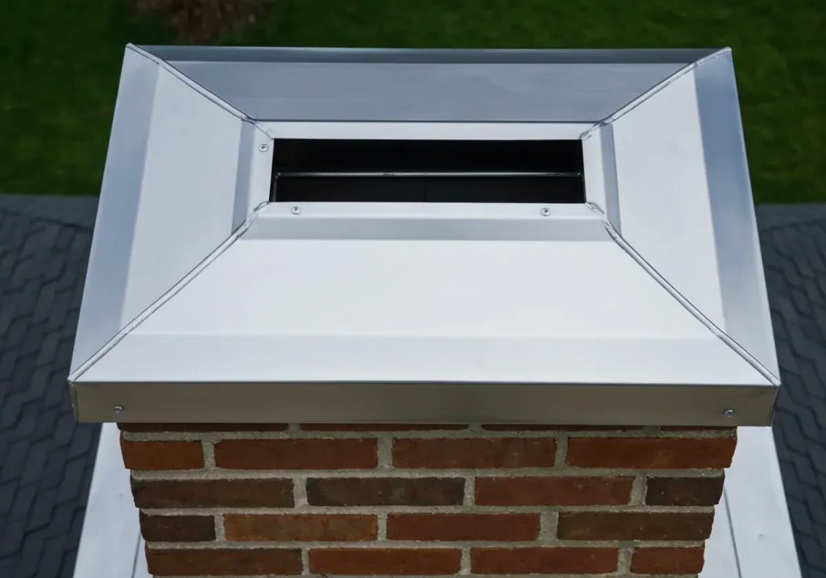 After — chimney cap installation: A bare, wide-open flue finally covered — a stainless cap against our nine months of rain.